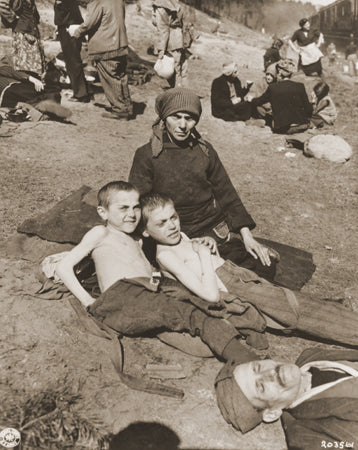 A woman and two children rest next to a stopped train.